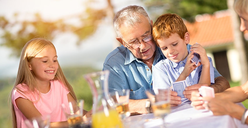 Grandfather teaches his grandson how to play a card game